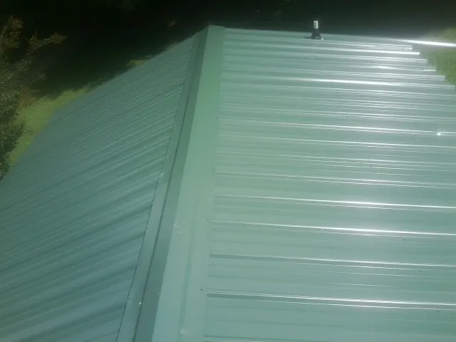 New green metal panels meeting at the ridge of a roof — Flat Roof Repair work by our crew in Cooke City