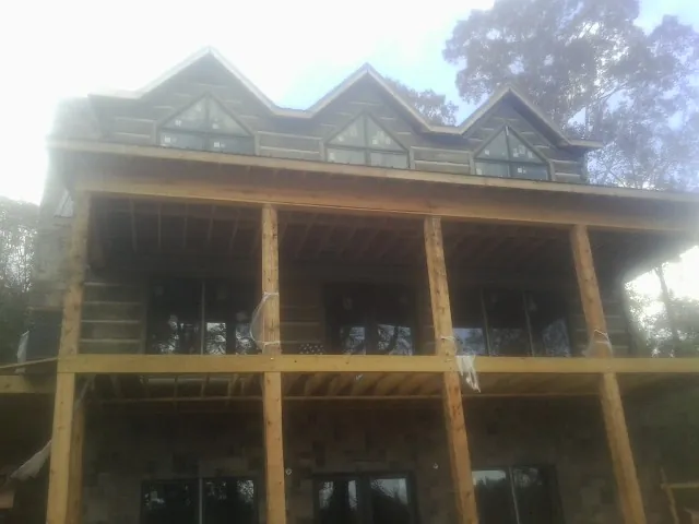 Dormers and porch framing on a large log home under construction — Roof Coating work by our crew in Cooke City