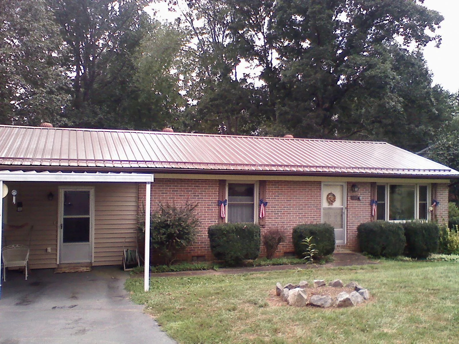 Bronze metal roof and carport on a brick ranch home — Roof Repair work by our crew in Cooke City