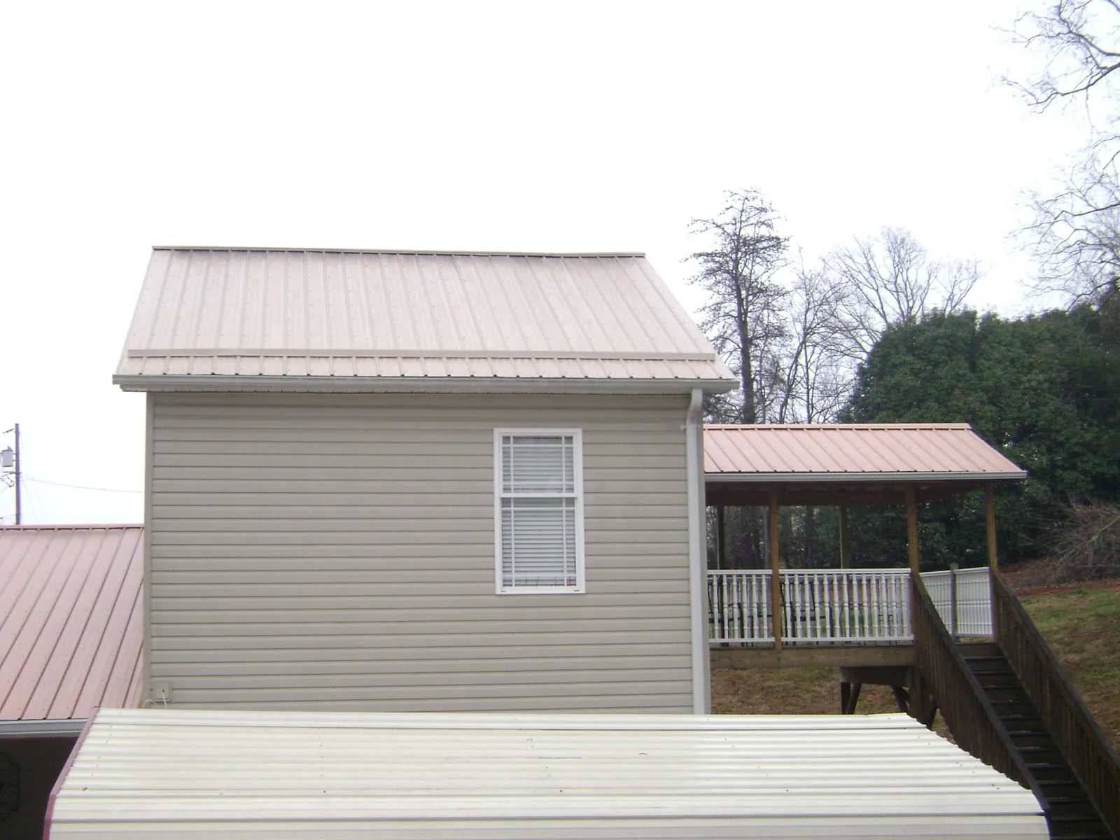 Tan metal roofs on a two story addition and attached porch, from a Roof Replacement job in Cooke City