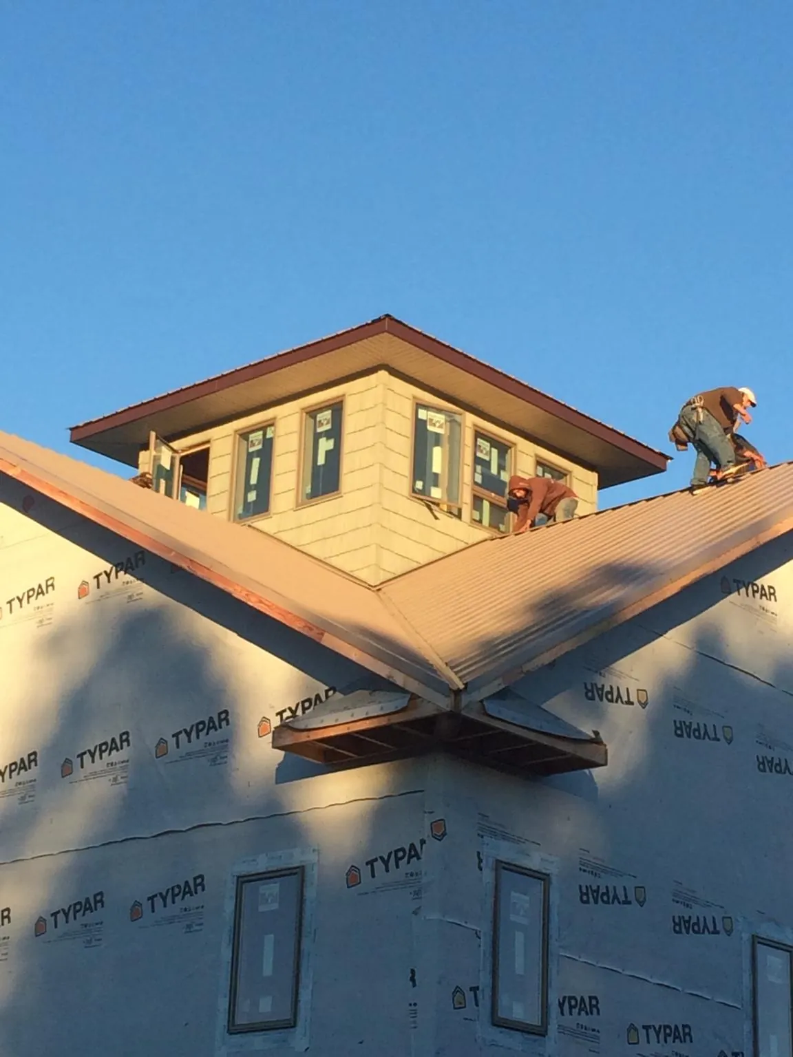 Roofers working around a rooftop cupola on a new metal roof at sunset — Roof Waterproofing in Cooke City by Roofing Brothers